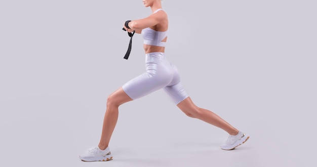 Image of a sports girl who trains with rubber bands in a white studio Fitness and bodybuilding concept