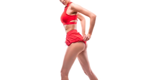 Image of a sports girl with pumped buttocks in a white studio Red sportswear Fitness and bodybuilding concept