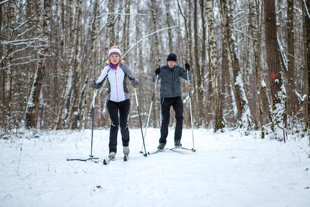 Image of sports woman and man skiing in winter forest