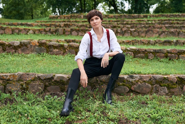 Image of a stylish beautiful woman in a white shirt black trousers and red suspenders The concept of style and fashion