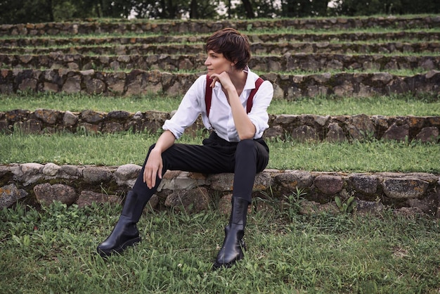 Image of a stylish beautiful woman in a white shirt black trousers and red suspenders The concept of style and fashion