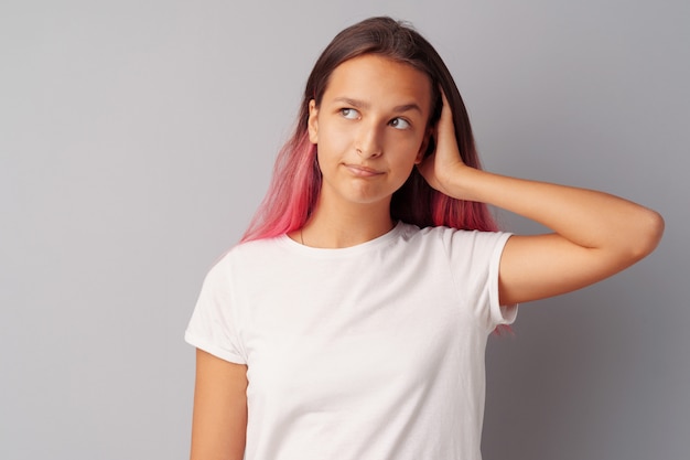 Image of thinking teen girl standing over a gray background