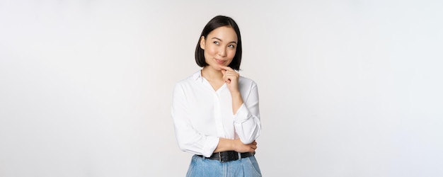 Image of thoughtful smiling woman has an idea scheming planning looking aside and thinking standing in office white blouse against studio background