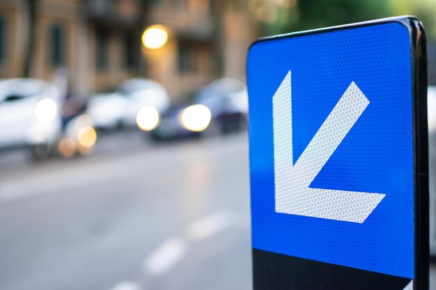 Photo image of traffic signal showing direction with some vehicles defocused in background