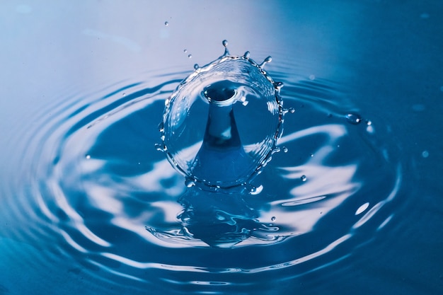 Image of Two water drops colliding on clean blue surface