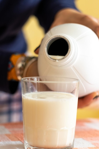 Image of an unrecognizable person pouring milk into a glass