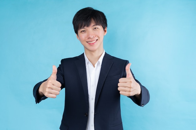 Image of young Asian businessman wearing a suit on a blue background