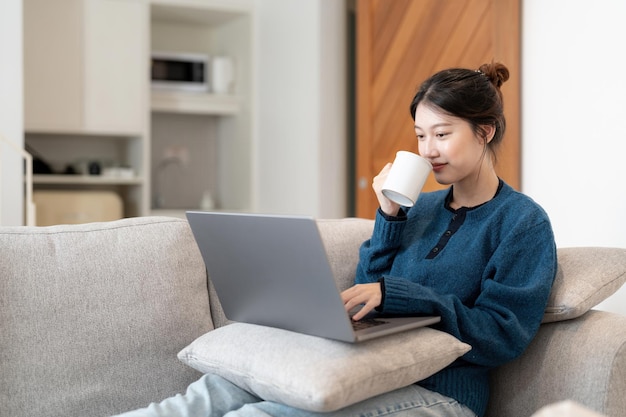 Image of young asian cheery happy positive cute beautiful business woman sit indoors in office using laptop computer