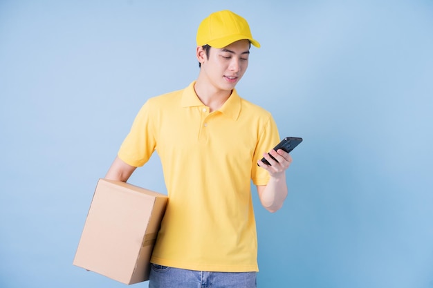 Image of young Asian delivery man on blue background