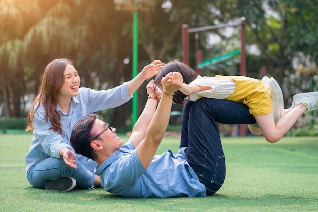 Image of young Asian family playing together at park