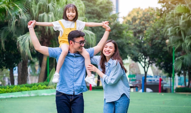 Image of young Asian family playing together at park