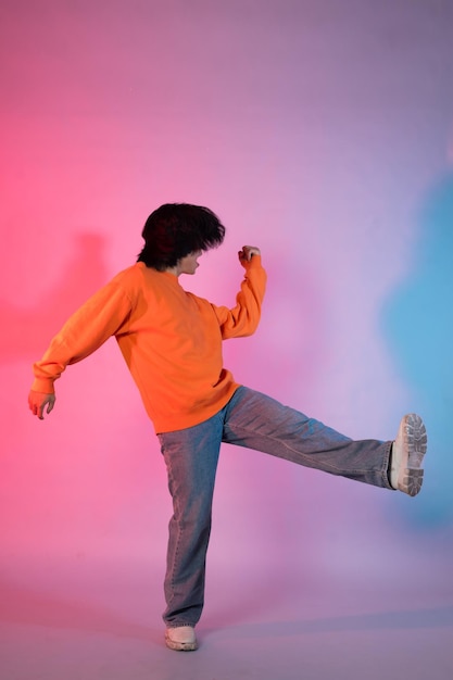 Image of a young Asian person dancing on a neon colored background