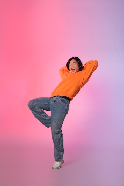 Image of a young Asian person dancing on a neon colored background