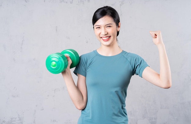 Image of young Asian woman holding dumbbell