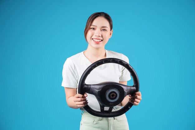 Image of young Asian woman holding steering wheel