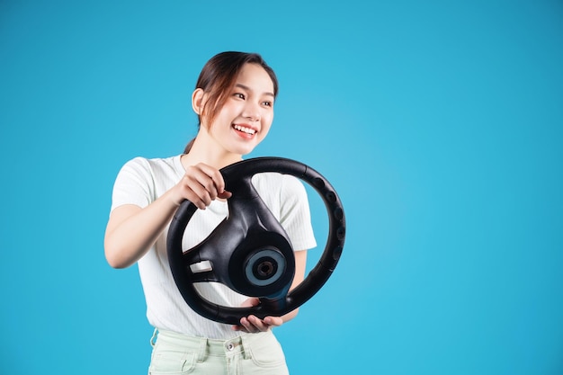 Image of young Asian woman holding steering wheel