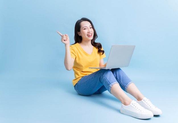 Image of young Asian woman sitting and using laptop