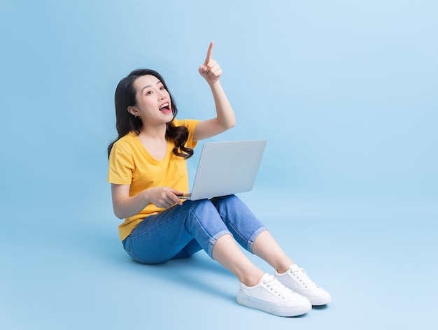 Image of young Asian woman sitting and using laptop