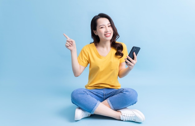 Image of young Asian woman sitting and using smartphone