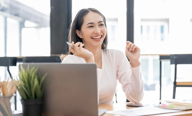 Image of young beautiful joyful woman laughing while working with laptop in office