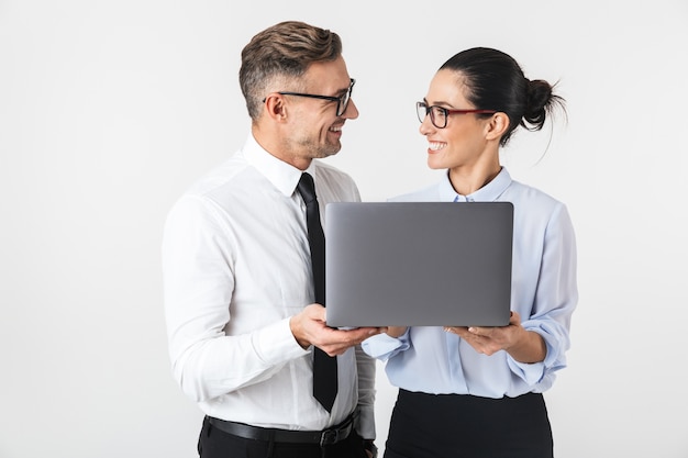 Image of young business colleagues couple isolated over white wall using laptop computer.