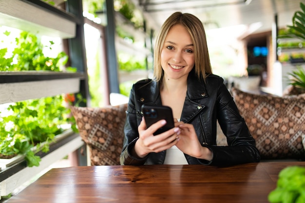 Image of young female reading sms on the phone in cafe