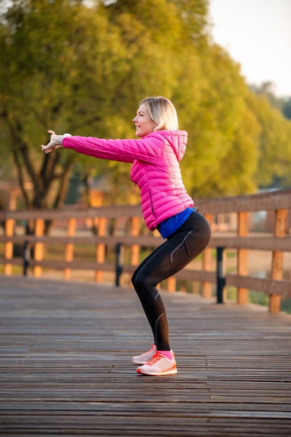 Image of young girl stretching in summer park in afternoon