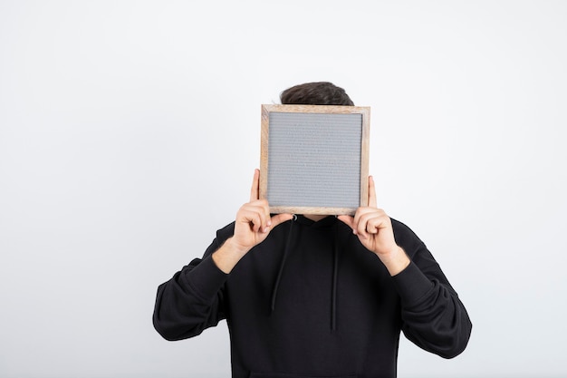 Image of young man in black hoodie holding empty frame