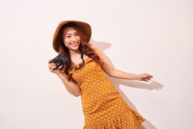 Image of young photographer woman isolated over beige wall wall holding camera.