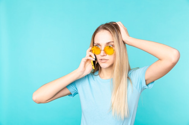 Image of a young woman holding smartphone and expressing amazement isolated on blue