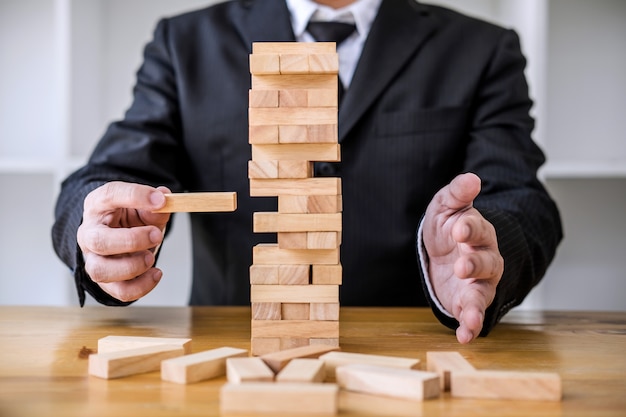 Photo images of hand of business people placing and pulling wood block on the tower