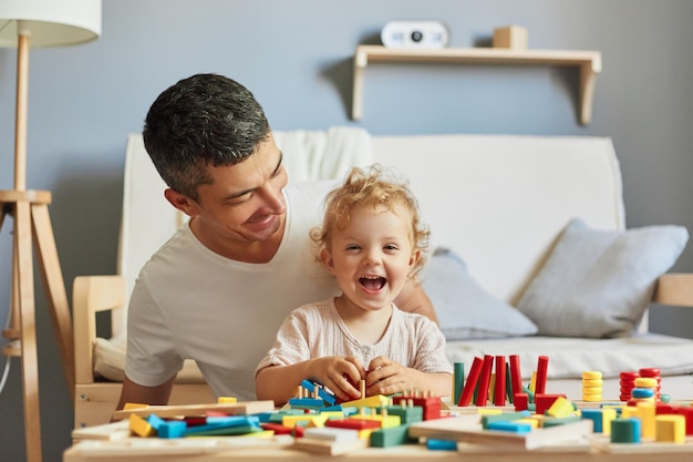 Imaginative storytelling games Cognitive puzzle challenges Montessori teaching method Baby girl playing sorter with her father in livingroom