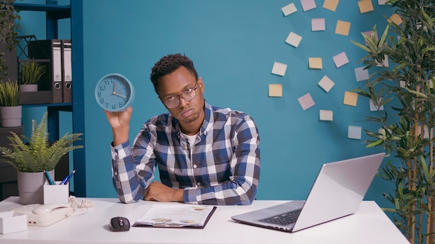 Impatient man waiting to finish work and checking time on clock, feeling tired and displeased. Serious upset person looking at watch to see deadline delay and time before break.