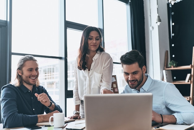 Important meeting. Young modern woman in smart casual wear pointing at laptop and smiling 