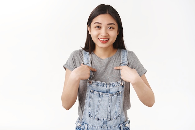 Impressed cheerful cute asian vietnamese girl surprised pointing herself happy was chosen pleased got cool unexpected surprise gift smiling delighted thanking opportunity white wall