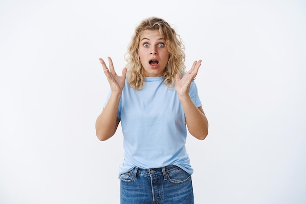 Impressed girl hear shocking rumor widen eyes and drop jaw holding hands raised from surprised and amazement standing in stupor as reacting to shocking news over white background