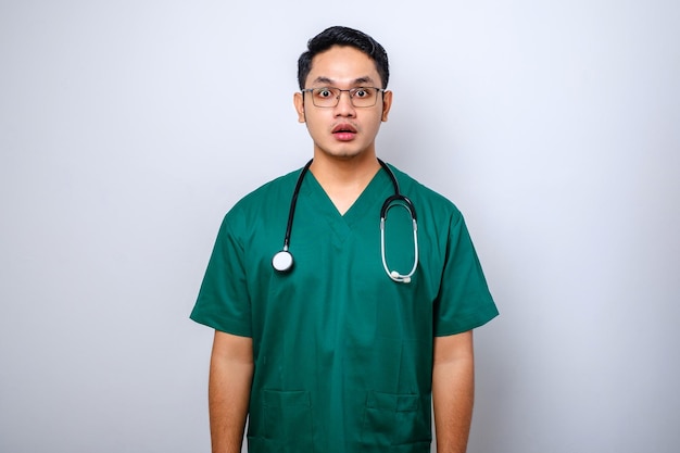 Impressed and surprised asian male nurse or doctor in scrubs drop jaw and stare at camera speechless looking amazed