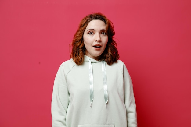 Impressed young beautiful girl in white sweater isolated on pink background