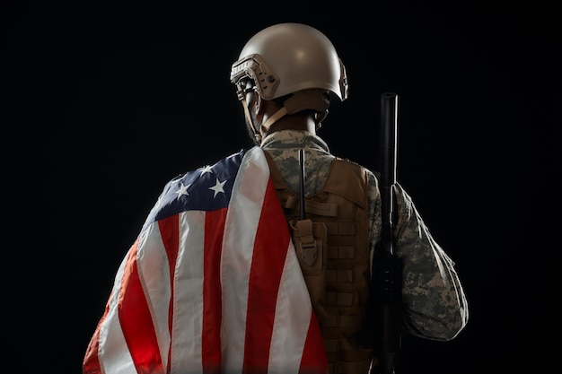 Photo incognito soldier holding american flag on shoulder.