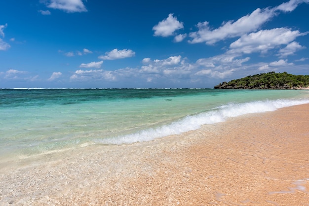 Incredible turquoise crystal clear water at seashore gentle waves breaking on sand blue sky