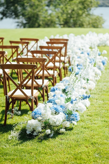 Incredibly beautiful outdoor ceremony on green grass and wooden chairs and fresh flowers wedding day