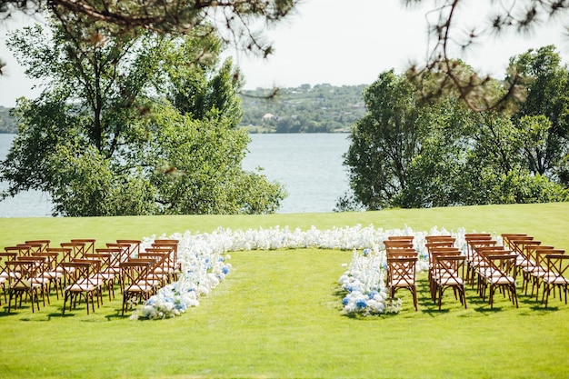 Incredibly beautiful outdoor ceremony on green grass and wooden chairs and fresh flowers Wedding day