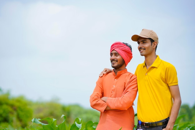 Indian agronomist with farmer at green agriculture field.