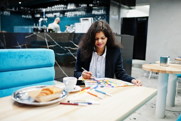 Indian artist woman wear formal paint picture while sitting at cafe