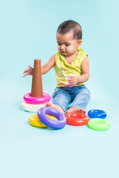 Indian or Asian Toddler or Infant or baby playing with toys or blocks while lying or sitting isolated over bright or colourful background