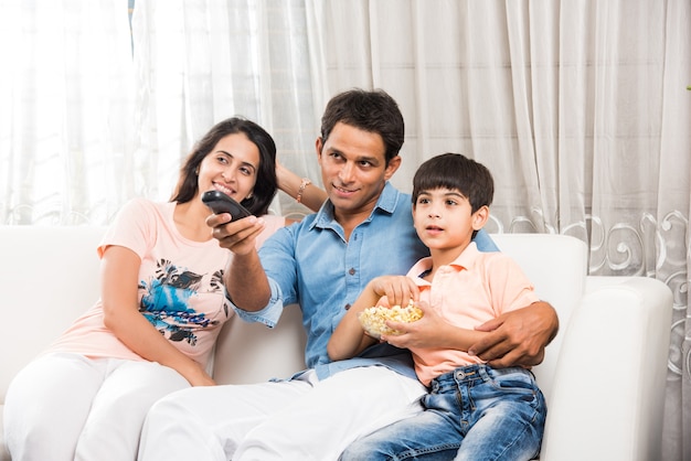 Indian asian young Family Watching TV Together while sitting at sofa, selective focus