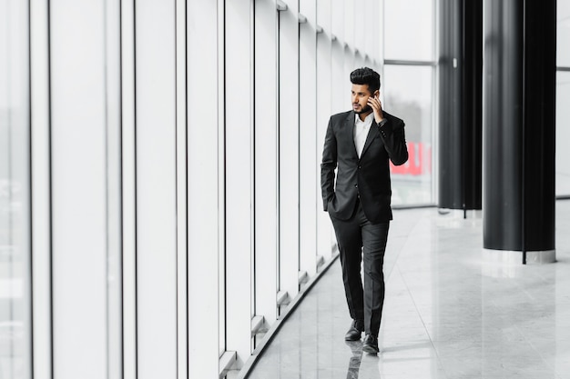 An Indian bearded man walks down the hallway of a modern office