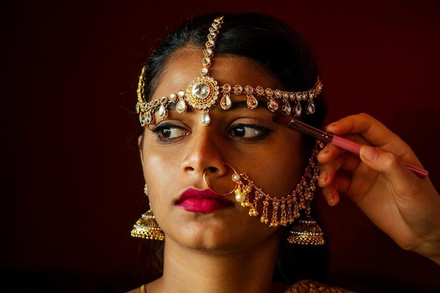 Indian beautiful female in golden rich jewelery and tradition saree face closeup professional makeup wearing bindi on head Artist doing to muslimgirl with bindis maang tikka nathnose Pin