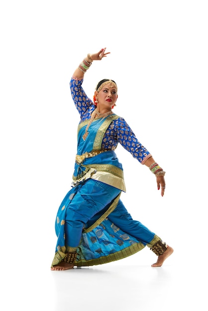 Indian beautiful woman dancing traditional dance in elegant blue dress against white studio