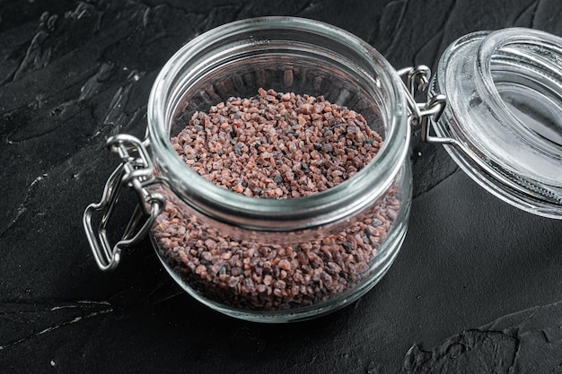 Indian Black salt, Kala namak hindi Healthy food concept set, in glass jar, on black stone background